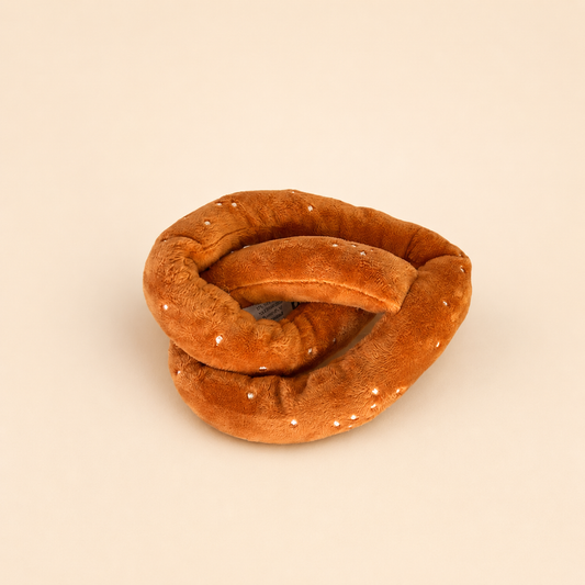 Pretzel-shaped plush dog toy on a neutral background